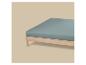 Bed met houten frame en blauw matras op een beige achtergrond.