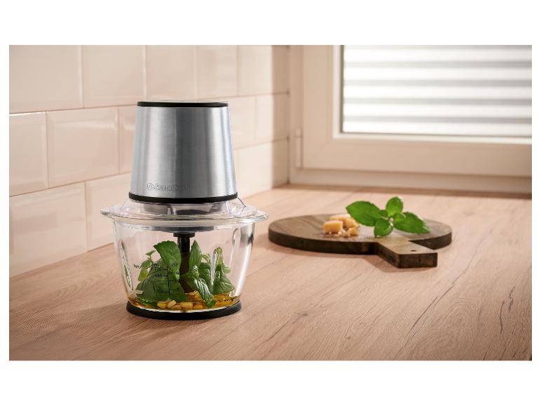 Voedselhakselaar met basilicum, olijfolie en kaas op een houten aanrecht.