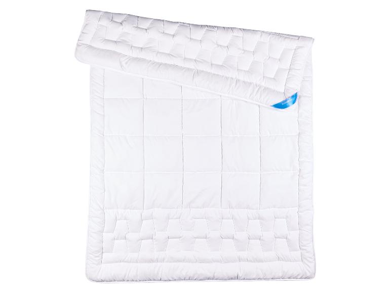 Wit gewatteerd dekbed met een geometrisch patroon en een blauw label.