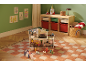Poppenhuis met meubels en poppen op een geruit vloerkleed in een kinderkamer.