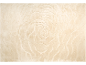 Beige vloerkleed met een reliëf spiraalpatroon dat op een roos lijkt.