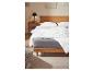 Een wit dekbed op een houten bed met een grijs matras.