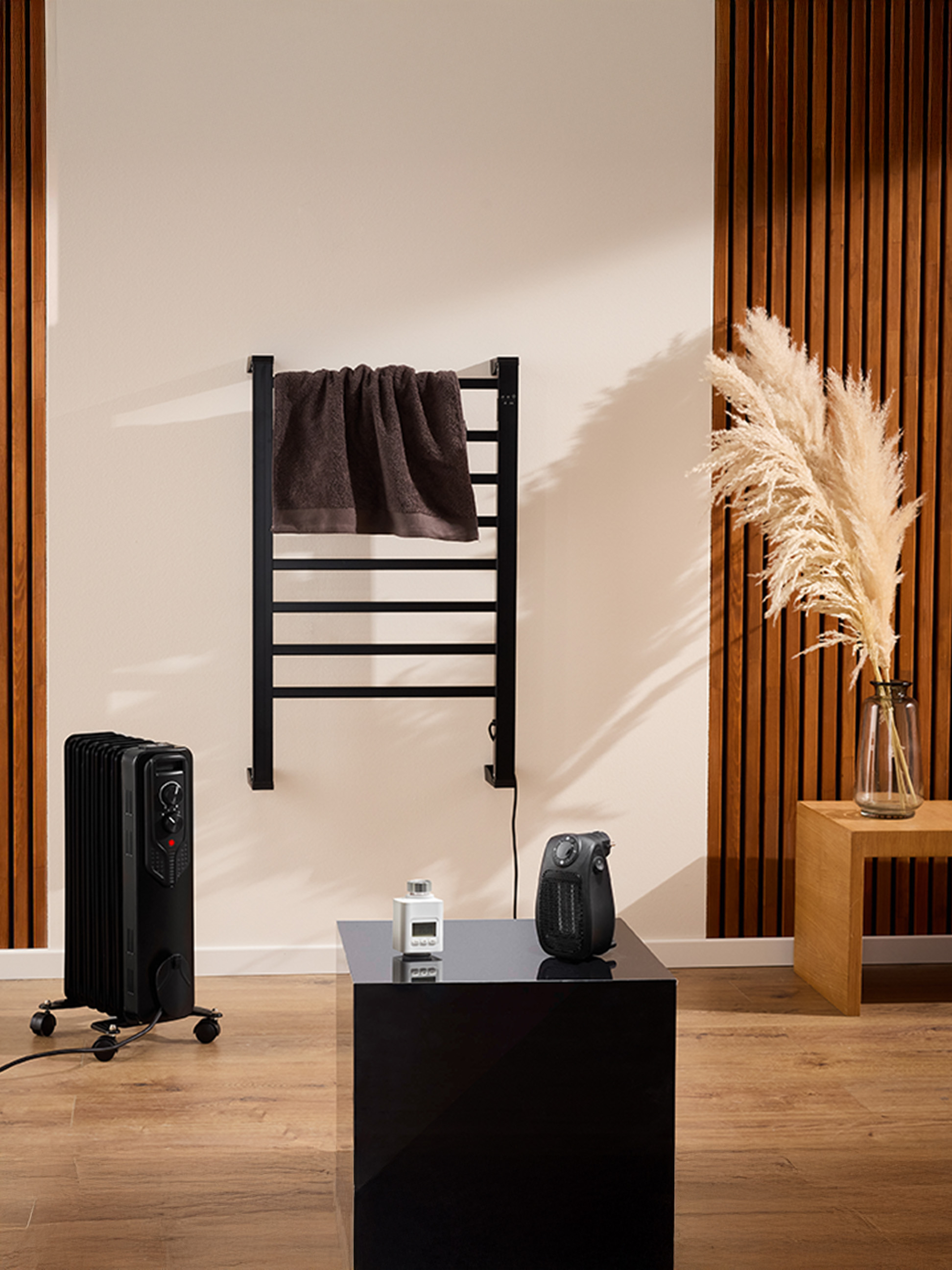 Een zwarte elektrische radiator en een aan de muur gemonteerde handdoekdroger in een moderne badkamer.