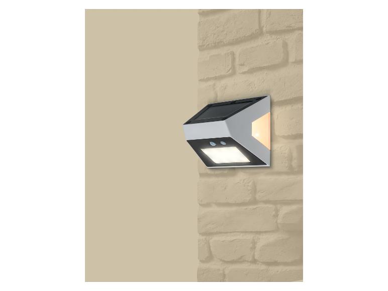 Solar wandlamp met bewegingssensor en twee lampen, gemonteerd op een bakstenen muur.
