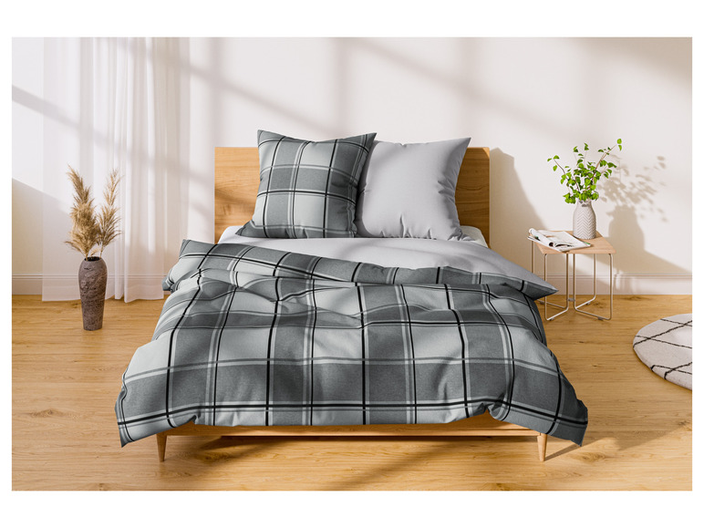 Een bed met een grijs-wit geruite dekbedovertrek en bijpassende kussens.