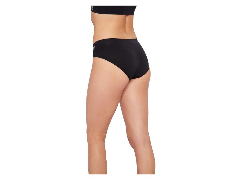 Vrouw draagt zwarte slip en zwarte sportbeha, zijaanzicht.