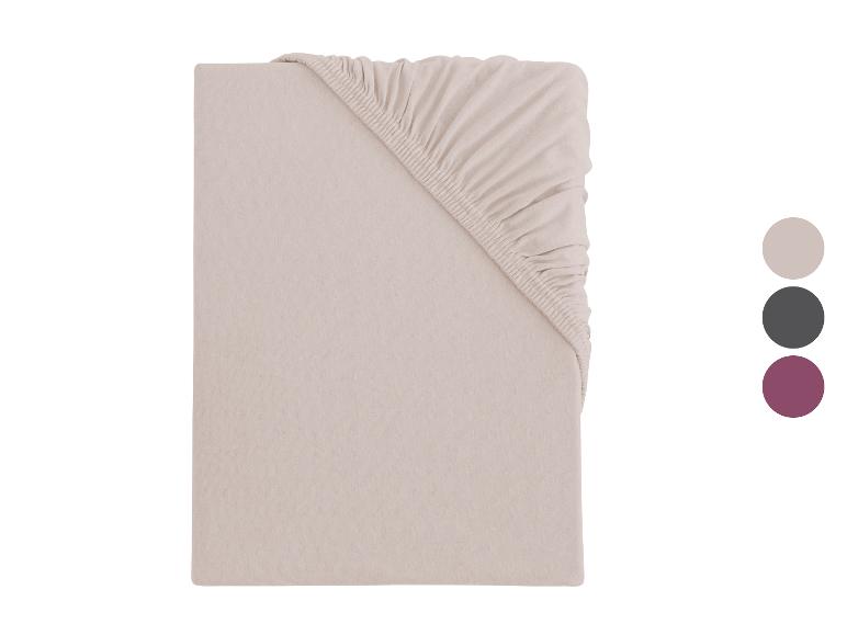 Beige hoeslaken met elastiek, opgevouwen, met kleurstaaltjes.