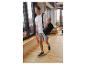 Man in wit T-shirt, grijze shorts en blauwe sneakers, draagt een zwarte sporttas.