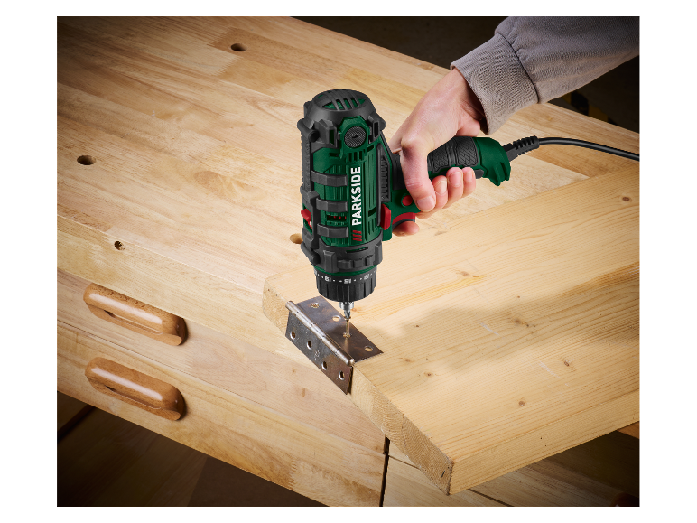 Iemand gebruikt een Parkside boormachine om een scharnier op een houten plank te bevestigen.