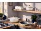 Elegant wit gietijzeren kookgerei en keukenaccessoires op een houten werkblad.