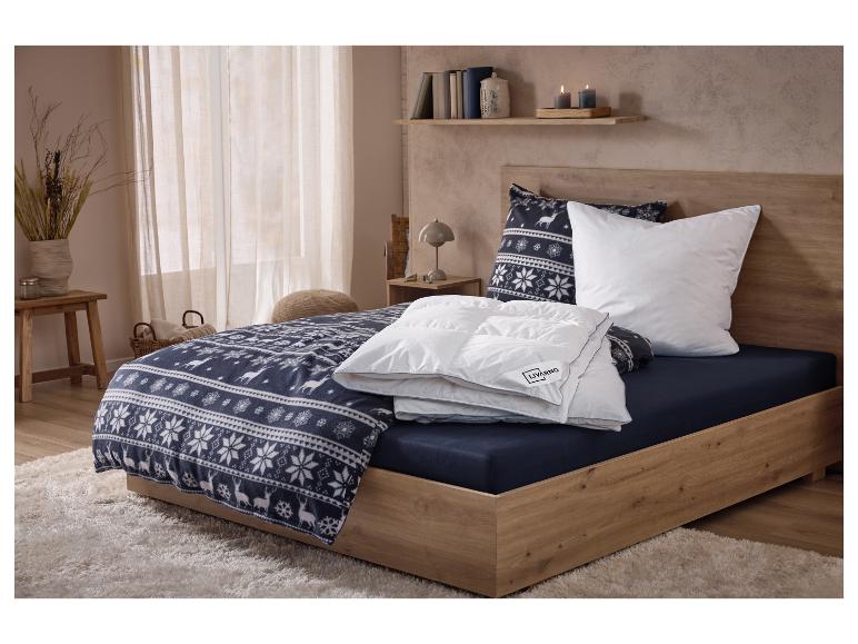 Slaapkamer met een houten bed, beddengoed met winterpatroon en een wit dekbed.