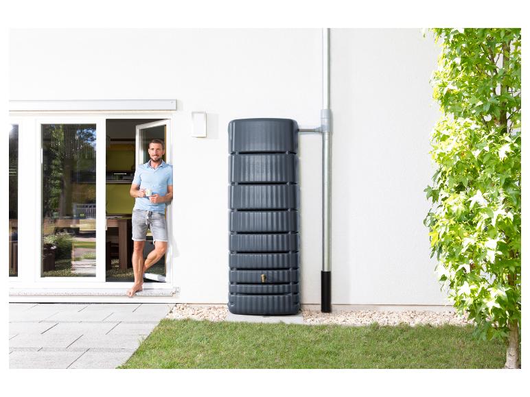 Man in deuropening met regenwatertank en regenpijp.