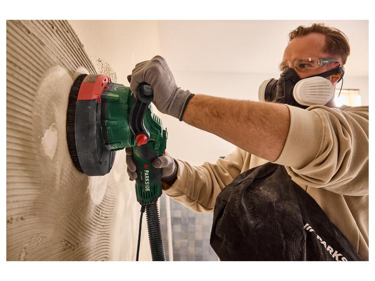 Een man gebruikt een Parkside schuurmachine om een muur glad te maken.