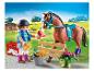 Playmobil ruiterfiguur voedt een paard, met paardenverzorgingsaccessoires.