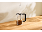 Water wordt in een cafetière met koffie op een houten tafel gegoten.