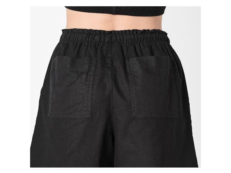 Zwarte, losvallende broek met elastische tailleband en opgestikte achterzakken.