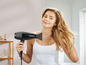 Een vrouw droogt haar haar met een zwarte Silvercrest föhn.