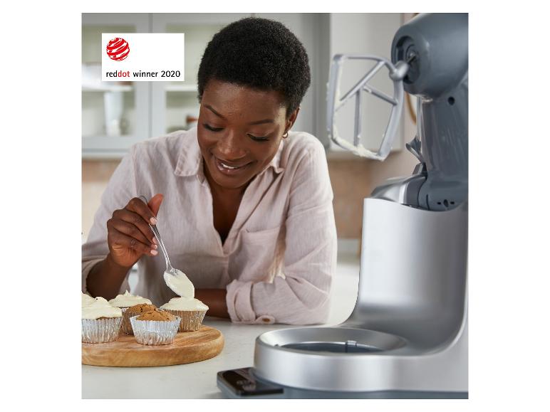 Vrouw versiert cupcakes, met een keukenmachine ernaast. Red Dot Award 2020.