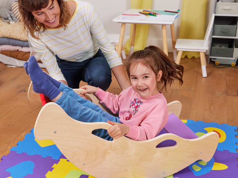 Een kind speelt op een houten schommeldier.