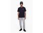 Man in zwart t-shirt, grijze joggingbroek, zwarte muts en zwarte sneakers.