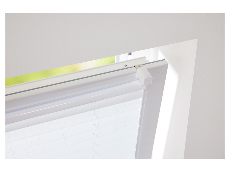 Witte plissegordijn bevestigd aan een raam