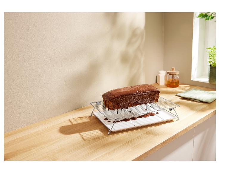 Een chocoladetaart op een taartrooster op een houten tafel.