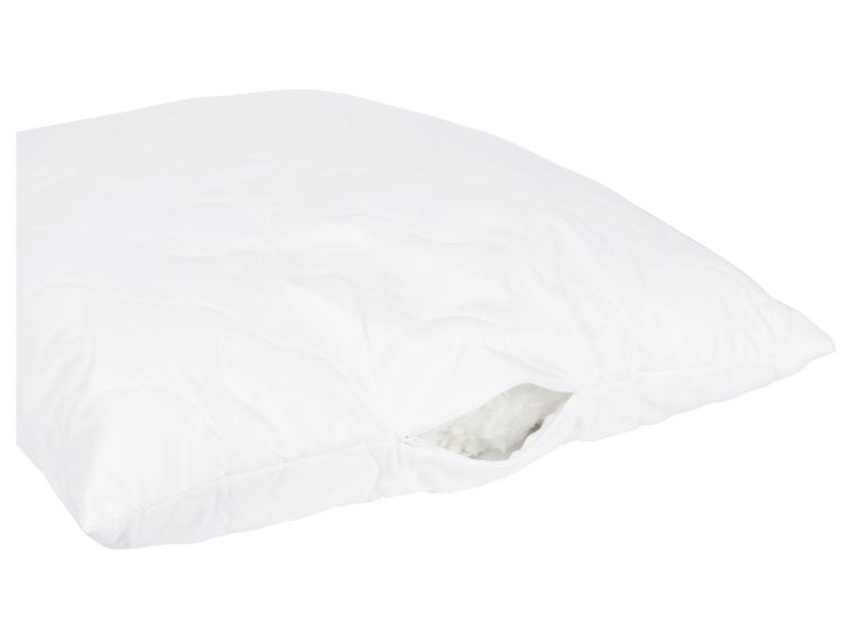 Wit gewatteerd kussen met rits, vulling zichtbaar.