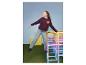 Meisje in ESMARA KIDS wide leg jeans en bordeauxrode trui op een kleurrijk klimrek