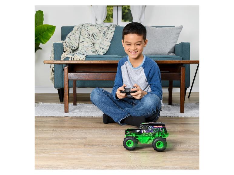 Een jongen speelt met een radiografisch bestuurbare Monster Jam Grave Digger truck.