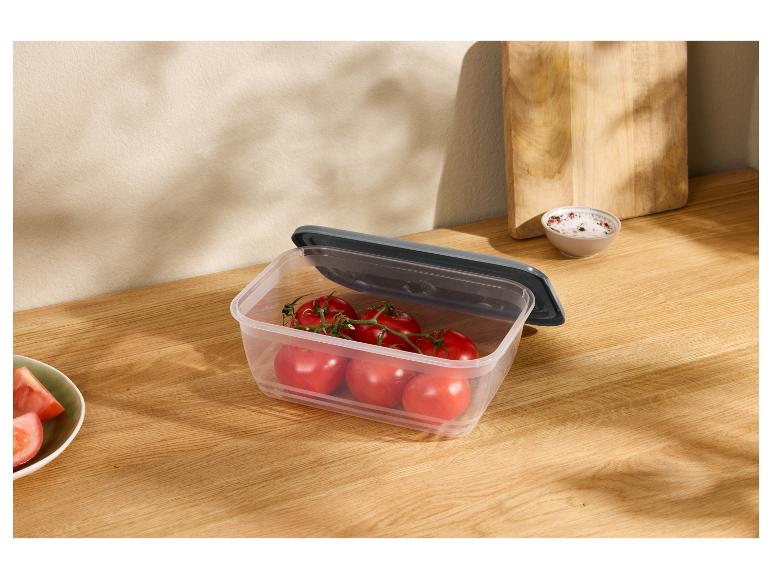 Voedselcontainer met tomaten op een houten aanrecht.