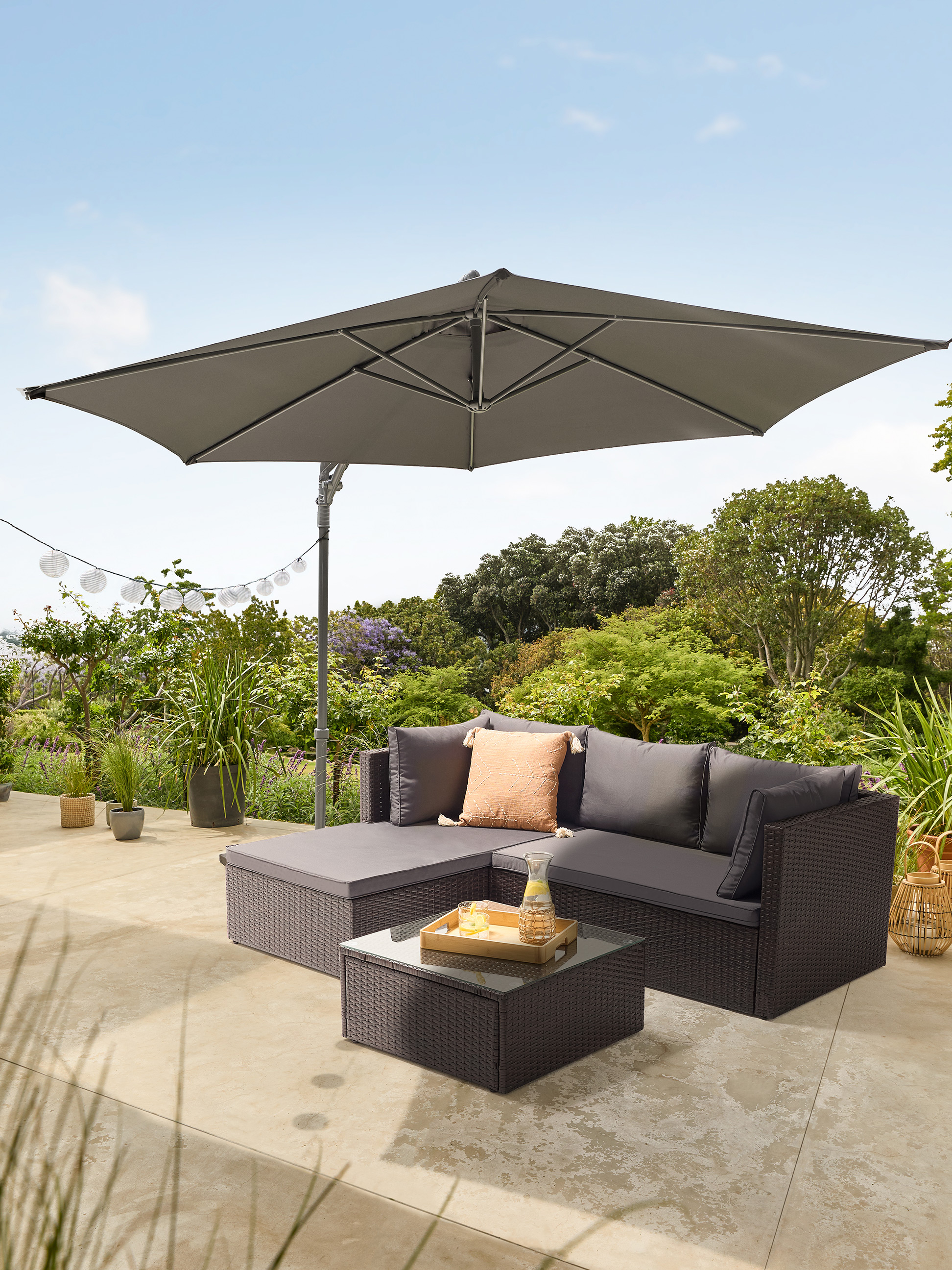 Tuinbankset met parasol en salontafel op een terras.