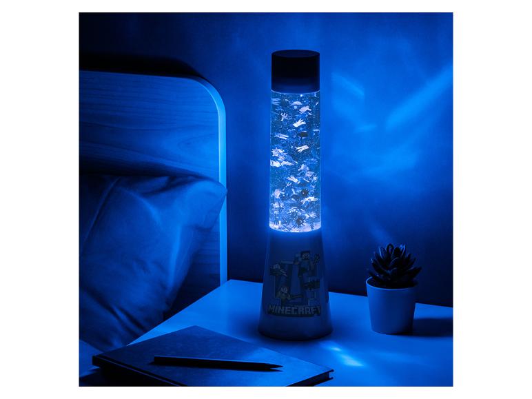 Videogame-thema lavalamp op een nachtkastje, met een notitieboekje en een plant.