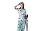 Vrouw in ski-uitrusting: bedrukt thermoshirt, blauwe broek, muts en skibril.