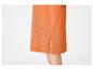 Detail van een oranje rok met zijsplit, toont een deel van een been.