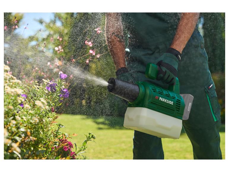 Tuinman besproeit planten met een groene handspuit, nevel zichtbaar.