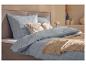 Bed met blauw geruit beddengoed, decoratieve kussens en een beige deken.