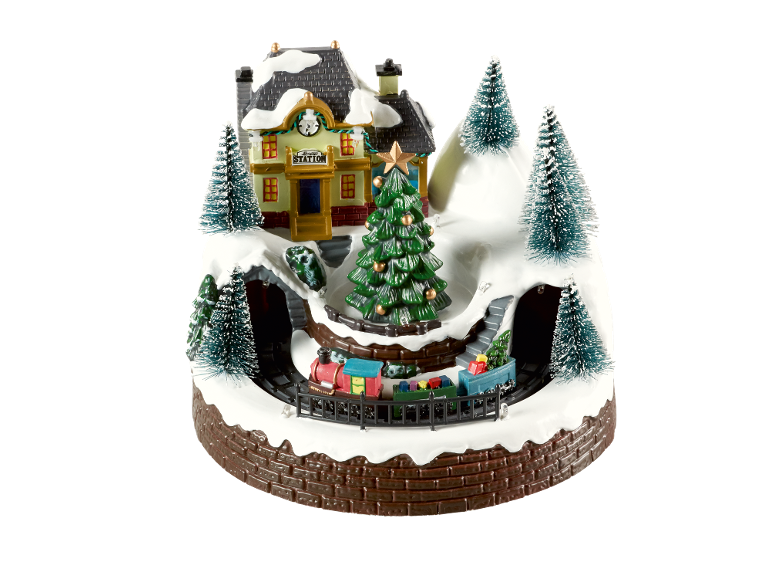 Kerstdorpdecoratie met een treinstation, bomen en een bewegende trein.