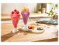 Twee ijscoupes met bessen en fruit op een houten tafel.