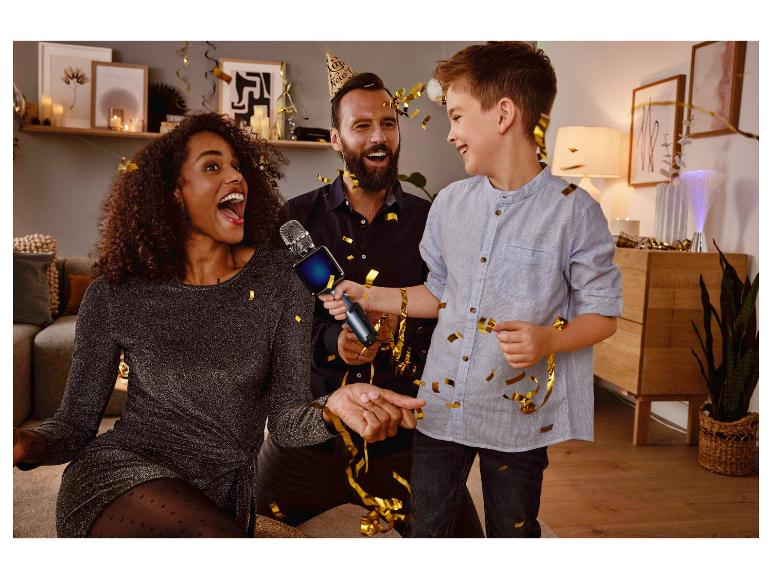 Een vrouw zingt in een karaoke microfoon tijdens een feestje met haar familie.