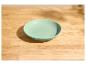 Mintgroene kom op een lichte houten tafel met schaduwen