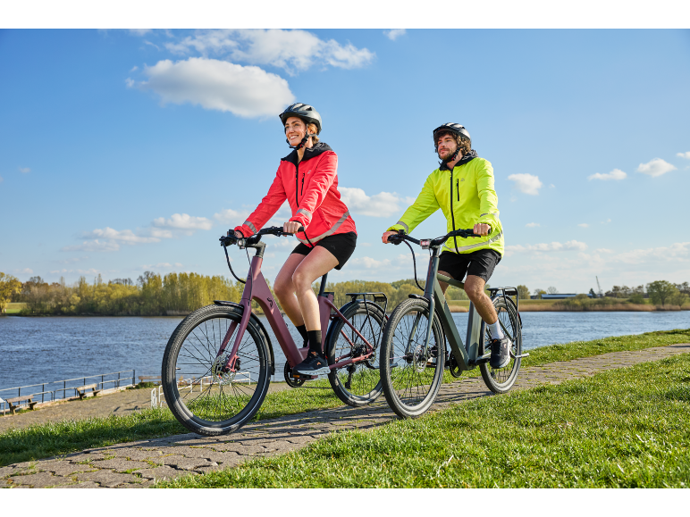 Een man en een vrouw fietsen op een verhard pad langs het water.