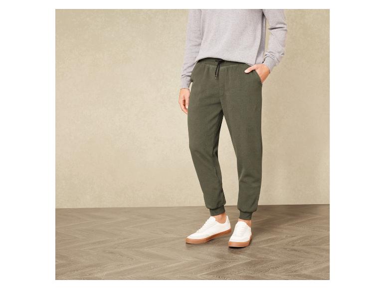 Man draagt groene joggingbroek en witte sneakers.