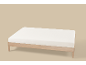 Licht matras op een houten bedframe met een lichtbruine achtergrond.