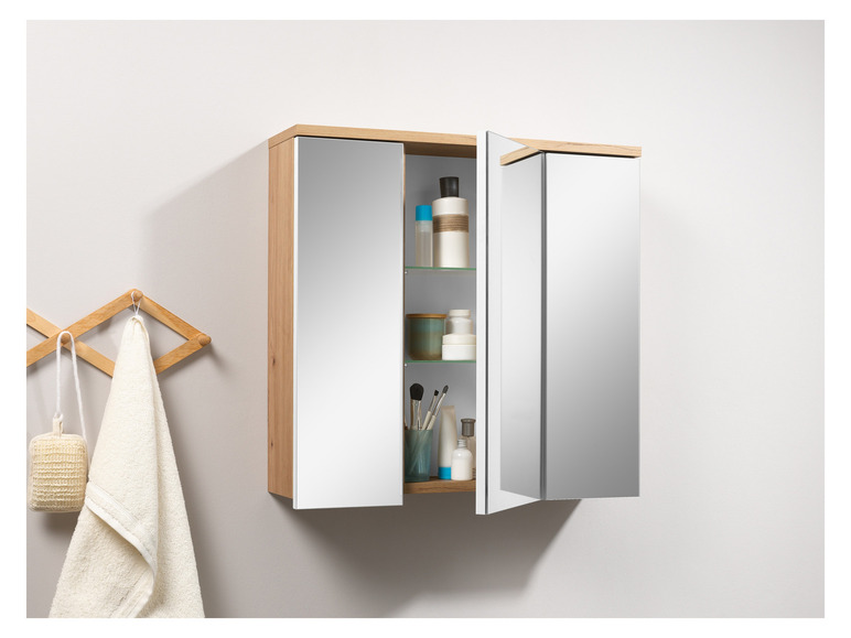 Een badkamerkastje met spiegeldeuren en een houten frame, gevuld met toiletartikelen.