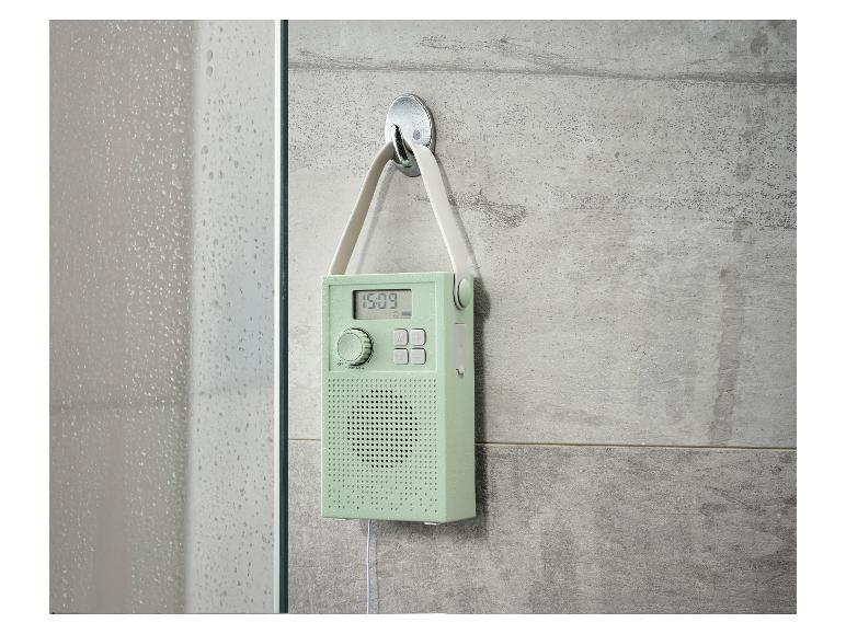 Mintgroene doucheradio met digitaal display hangend aan een betegelde muur.