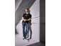 Man in zwart T-shirt en jeans, groen-witte sneakers, leunend tegen een muur.