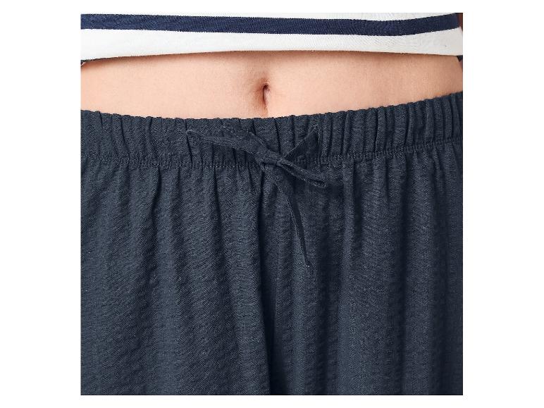 Middenrif van een persoon met een gestreepte top en marineblauwe pyjamabroek met trekkoord.