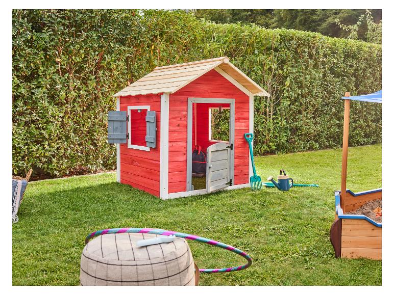 Rood houten speelhuisje met zandbak en buitenspeelgoed in een groene tuin.