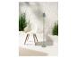 Designstoel, staande lamp en groene planten in een minimalistische setting.