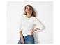Vrouw in een wit shirt met lange mouwen en blauwe jeans, lachend en omhoogkijkend.
